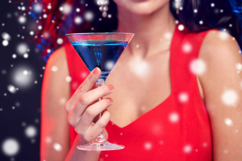 穿红色衣服的女人手拿盛满蓝色鸡尾酒杯