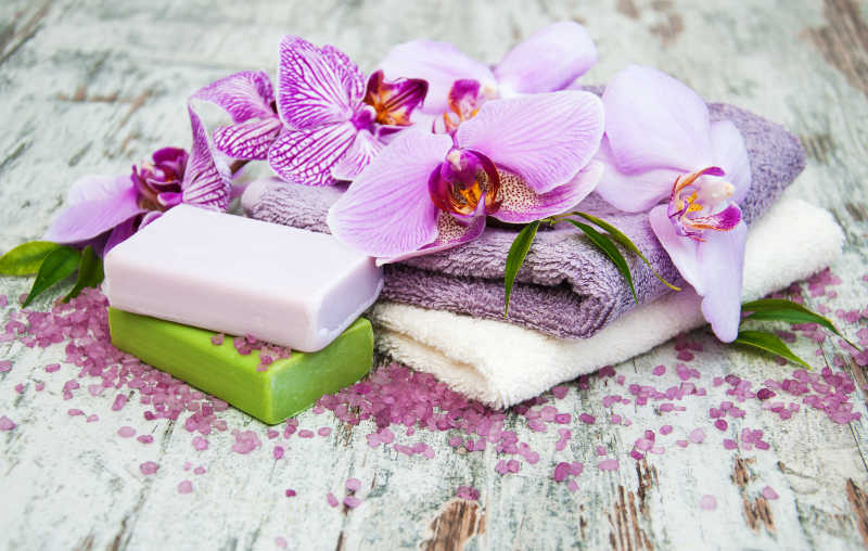 木桌上的手工皂毛巾和紫兰花