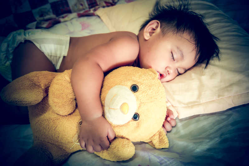 孩子抱着一只泰迪熊睡觉