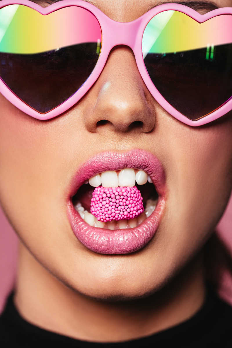 美丽时尚的年轻女人咬着糖果在嘴里