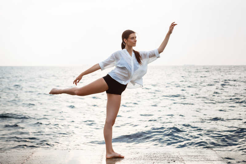 年轻漂亮的芭蕾舞演员在海面上里练习舞蹈