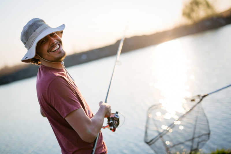 年轻人在日落时分在湖上钓鱼