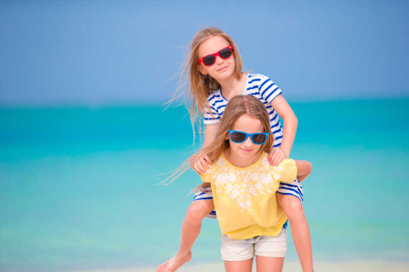 2个可爱的小女孩在白色海滩度假时玩得很开心