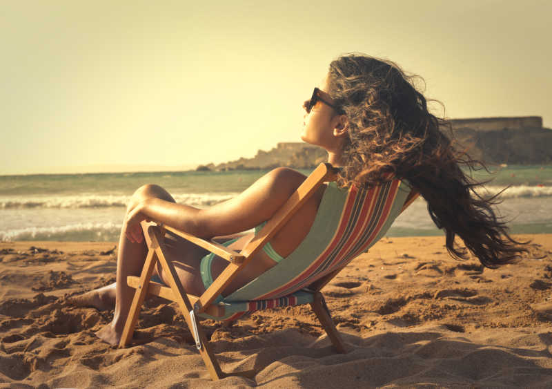 海滩上坐着躺椅放松的女子