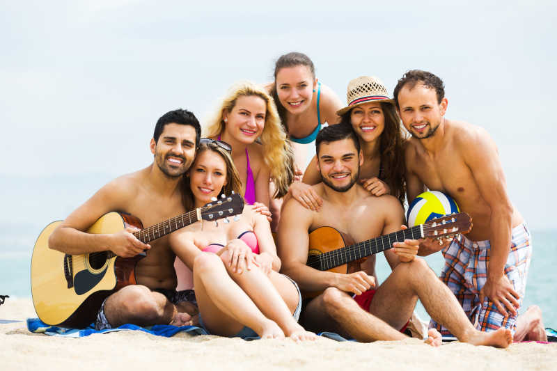 沙滩上拿着吉它的年轻人群