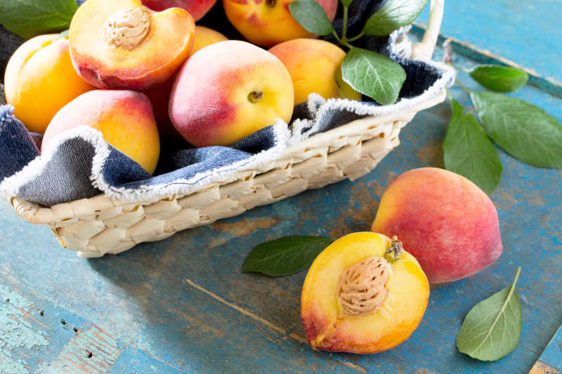 在老式木桌上的柳条筐里收获新鲜成熟的桃子