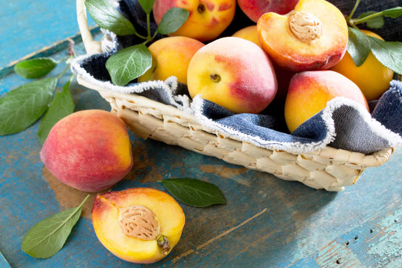 在老式木桌上的柳条筐里新鲜成熟的桃子