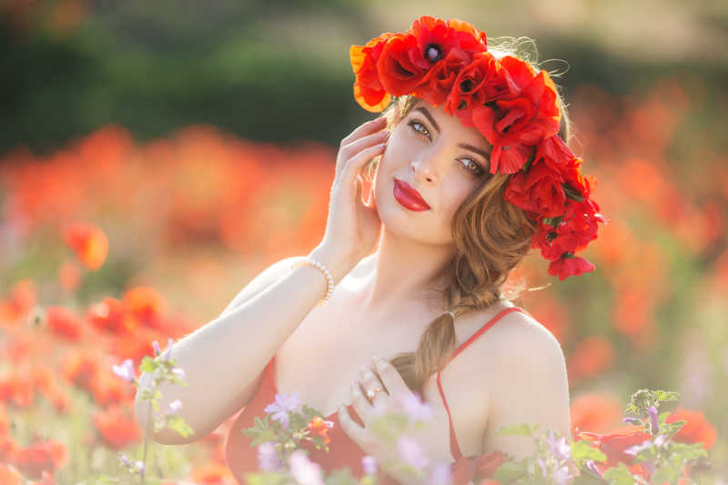 站在红色花丛中抚摸自己脸的美女
