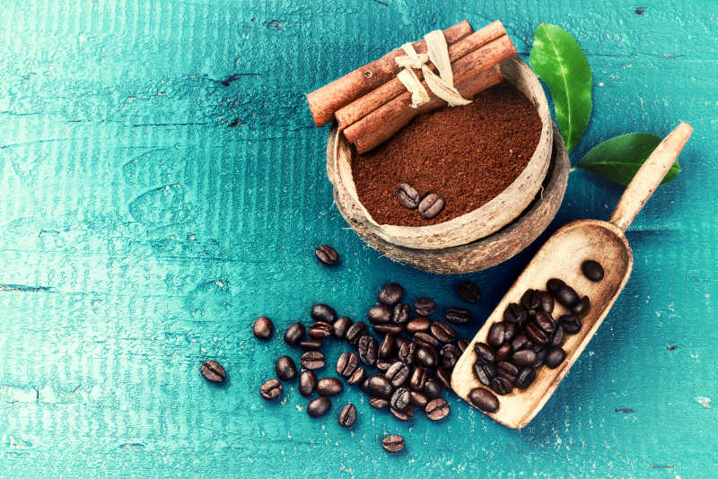 在蓝色木底上烘焙咖啡豆配上咖啡和肉桂枝