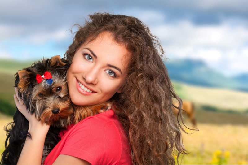 草地上穿红衣服的女人抱着一只狗