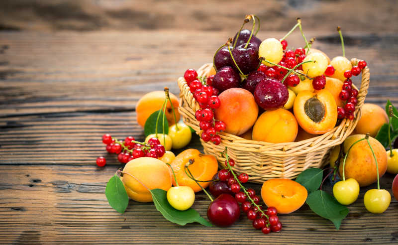 木质桌面上柳条筐里新鲜的夏日水果