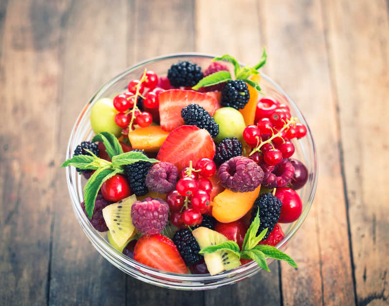 木质桌面上玻璃碗里的新鲜的夏日水果