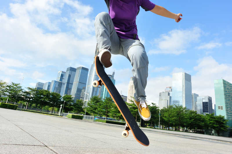在城市空地上玩滑板跳跃的年轻人