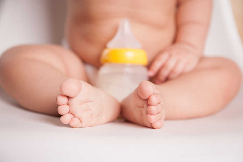 婴儿的脚旁边放着奶瓶