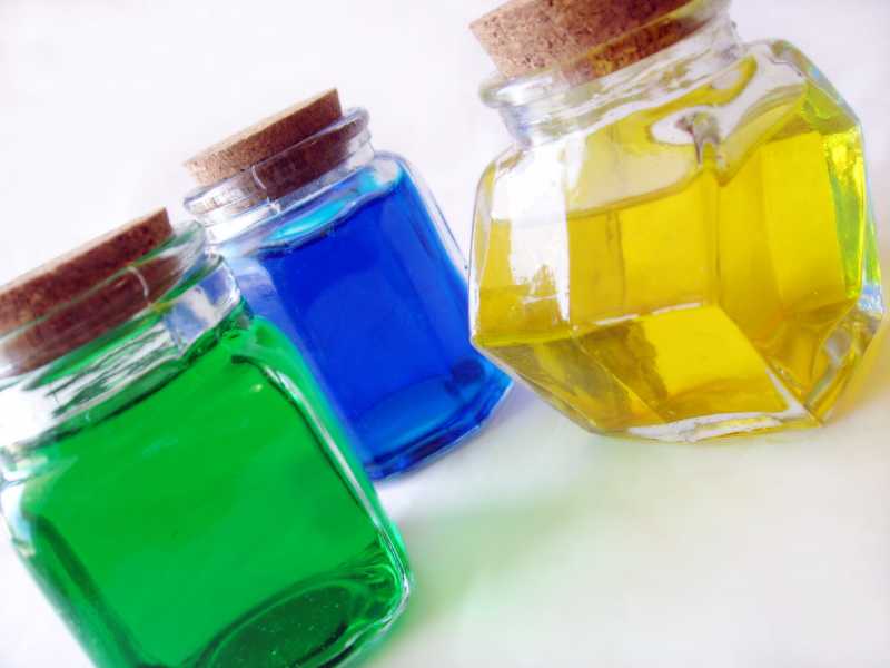 白色背景上三个不同形状的玻璃瓶里装着彩色液体