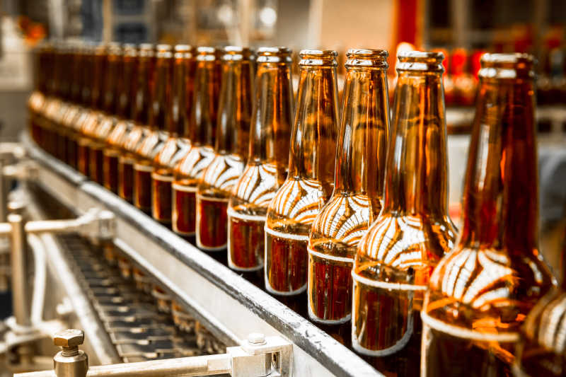 工厂传送带上整齐的棕色啤酒瓶