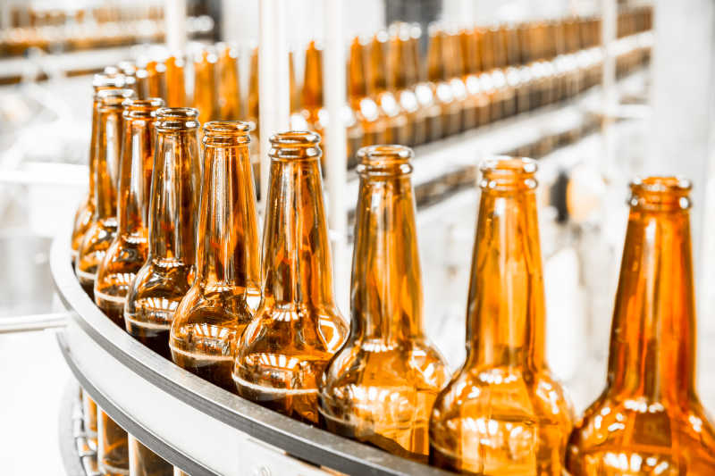 工厂里传送带上的整齐的黄色啤酒瓶