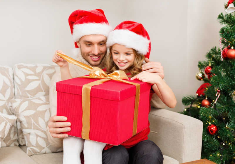 微笑的父亲和女儿打开圣诞礼物
