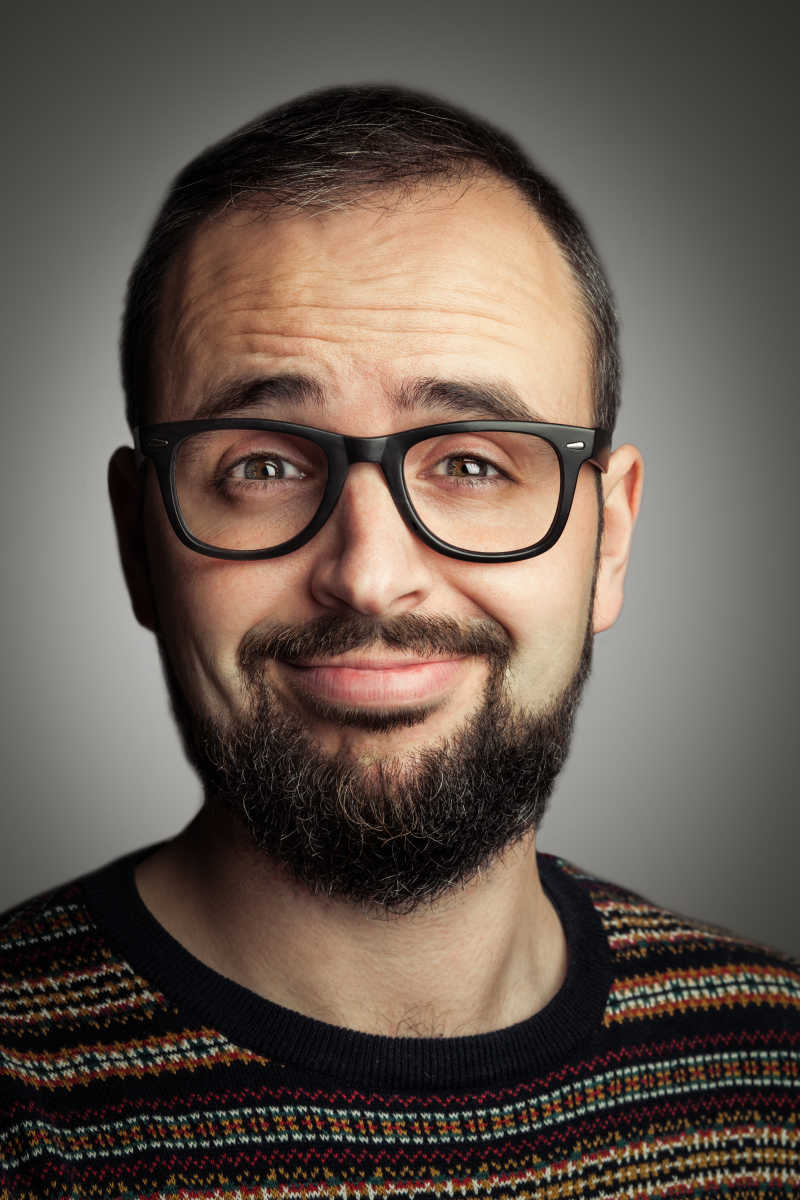 灰色背景下戴着眼镜有络腮胡的微笑的男人