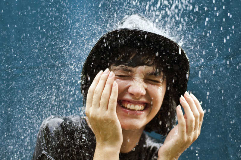 戴着帽子在雨中淋雨的年轻女性
