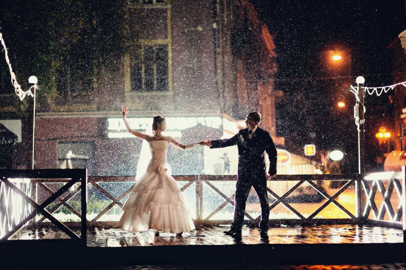 夜晚时在雨中跳舞新娘和新郎