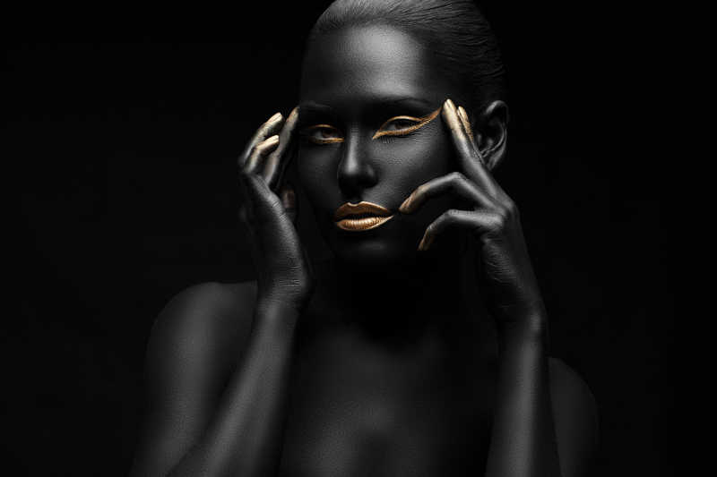 黑色背景上全身涂满黑色颜料的女人的手指按在太阳穴