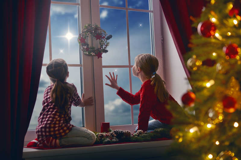 圣诞节晚上一起坐在窗前看夜空的姐妹俩