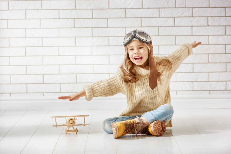 坐在地上玩飞机模型的小女孩