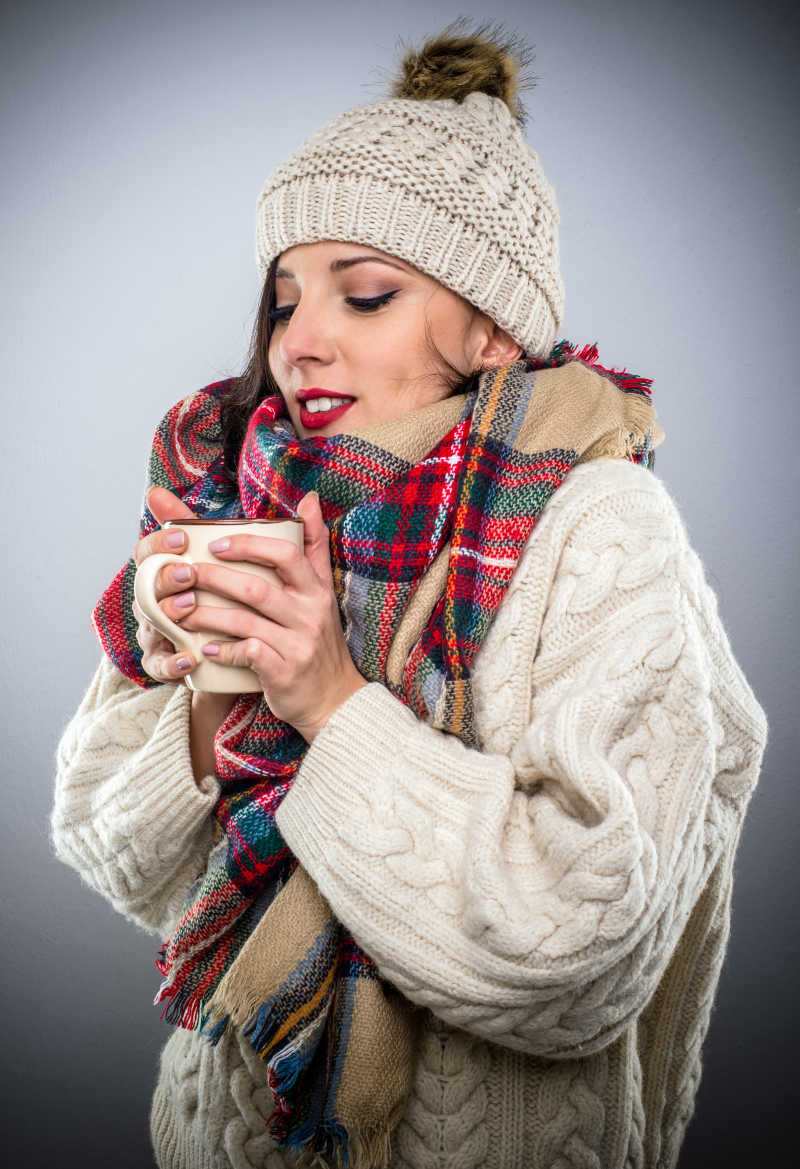 戴围巾的女人享用一杯热咖啡