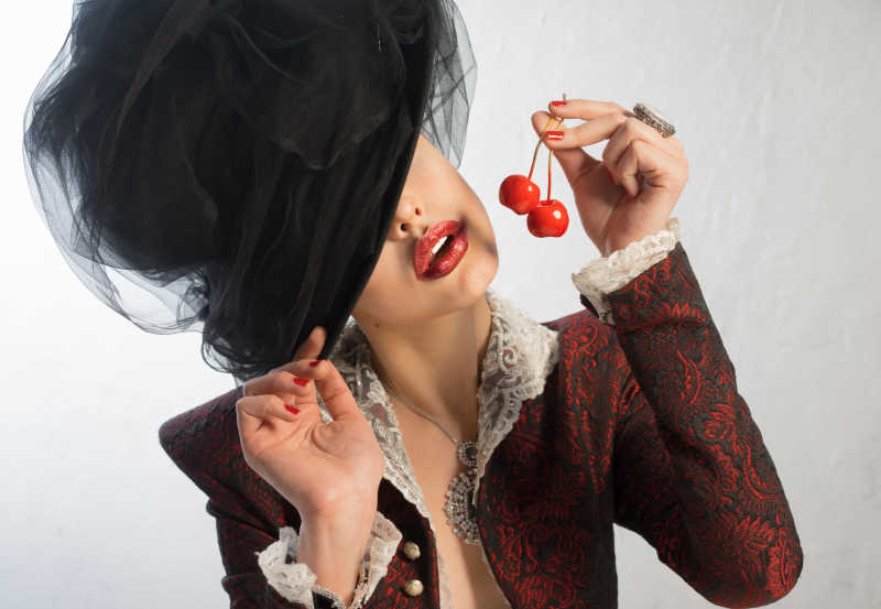 时尚复古的女人在吃樱桃