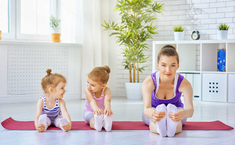 年轻妈妈在教孩子练瑜伽