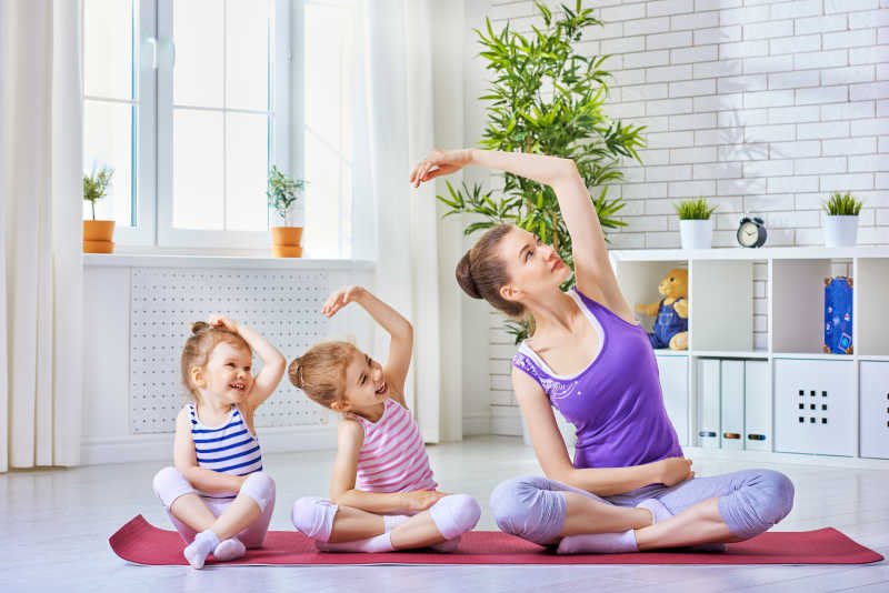 年轻妈妈带领两个小孩子练习瑜伽