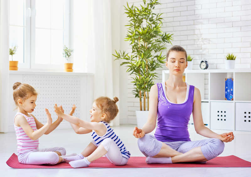 练习瑜伽的母亲和淘气的小孩子们