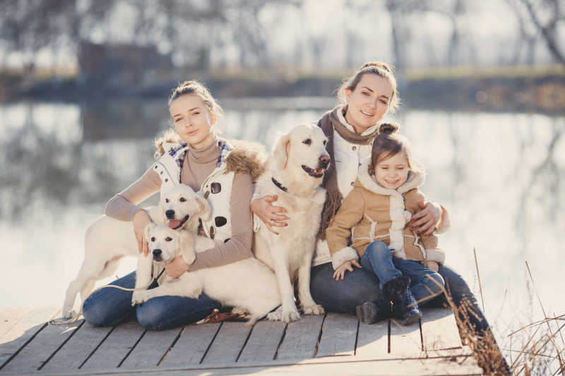 湖边抱着宠物狗拍照的幸福家庭