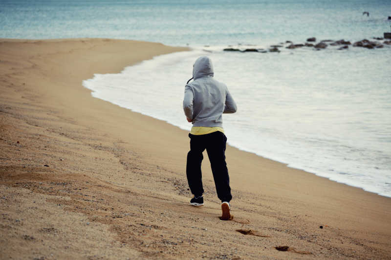 清晨在海边向远方跑步的男人