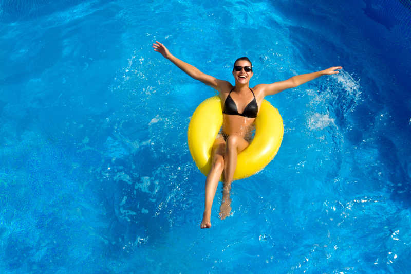 泳池中坐在黄色泳圈上的黑发女人
