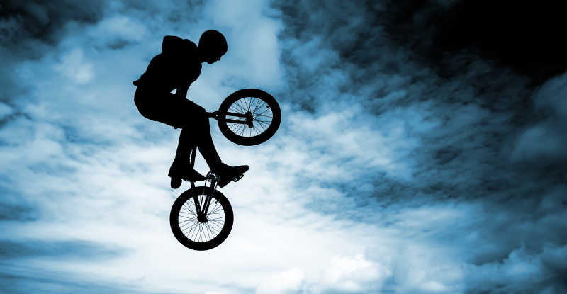 在蓝天背景下骑着BMX自行车的男子纵身一跳