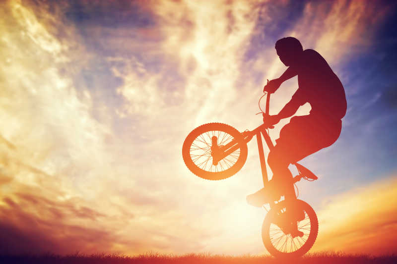 男子骑着自行车在落日的天空戏法表演