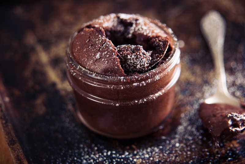 褐色背景下的在玻璃缸里烘焙的巧克力蛋糕