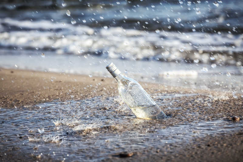 在雨中沙滩上的玻璃瓶子