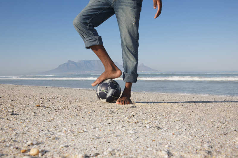 沙滩上脚踩足球的人