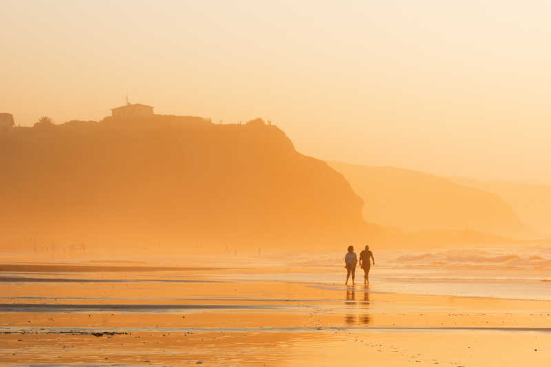 日落时分在海滩散步的情侣