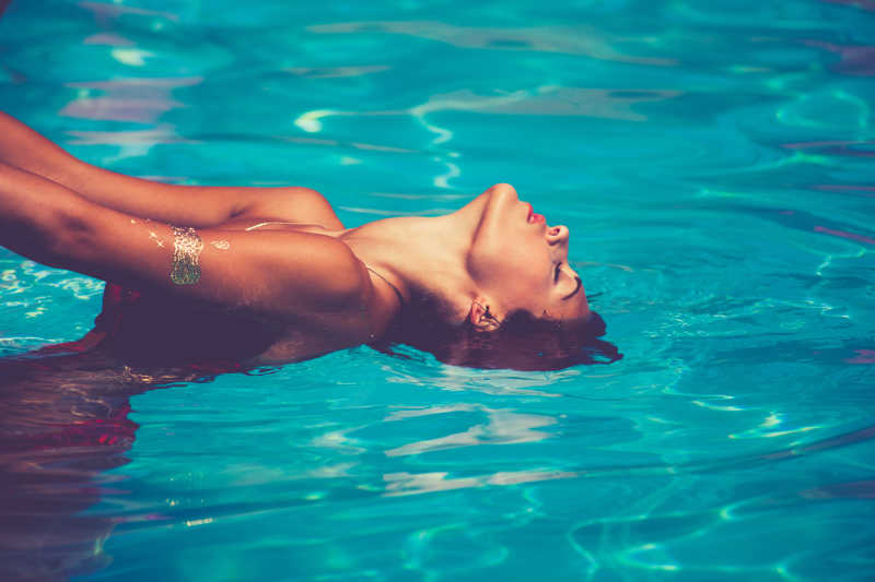 年轻漂亮女人在游泳池里把头向后仰着看