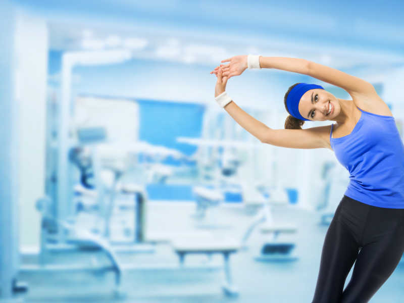 穿蓝色吊带的女孩在健身房里锻炼