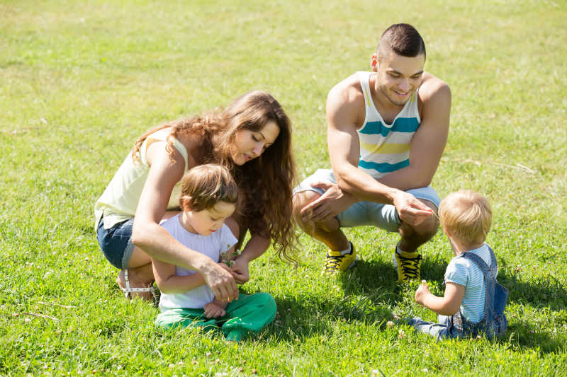 夏日草地上年轻父母和两个孩子