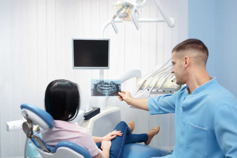 在牙科诊所展示病人X光的牙科医生