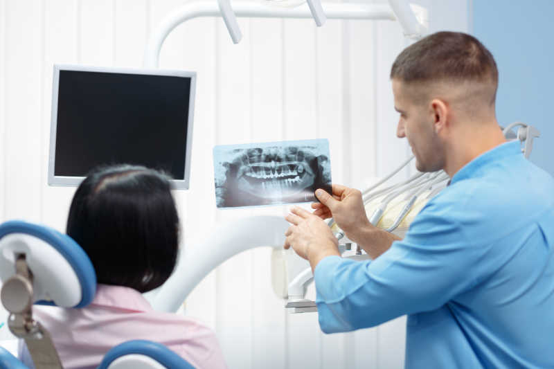 在牙科诊所展示病人X光的男性牙科医生