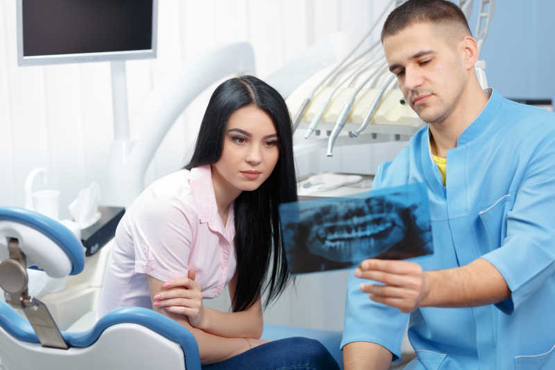 男性牙科医生给女患者看x光照片