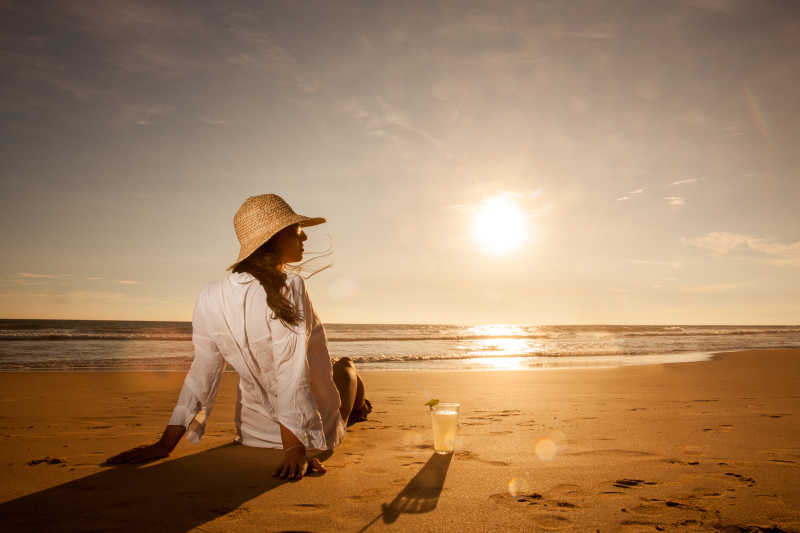 坐在沙滩上戴着草帽的年轻女子