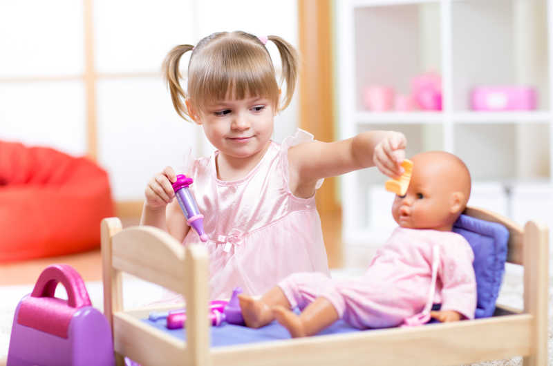 在房间里玩洋娃娃的小女孩